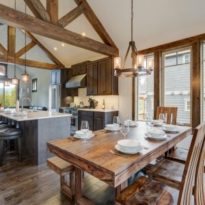 Amazing dining room near modern and rustic luxury kitchen with vaulted ceiling and wooden beams, long island with white quarts countertop and dark wood cabinets.